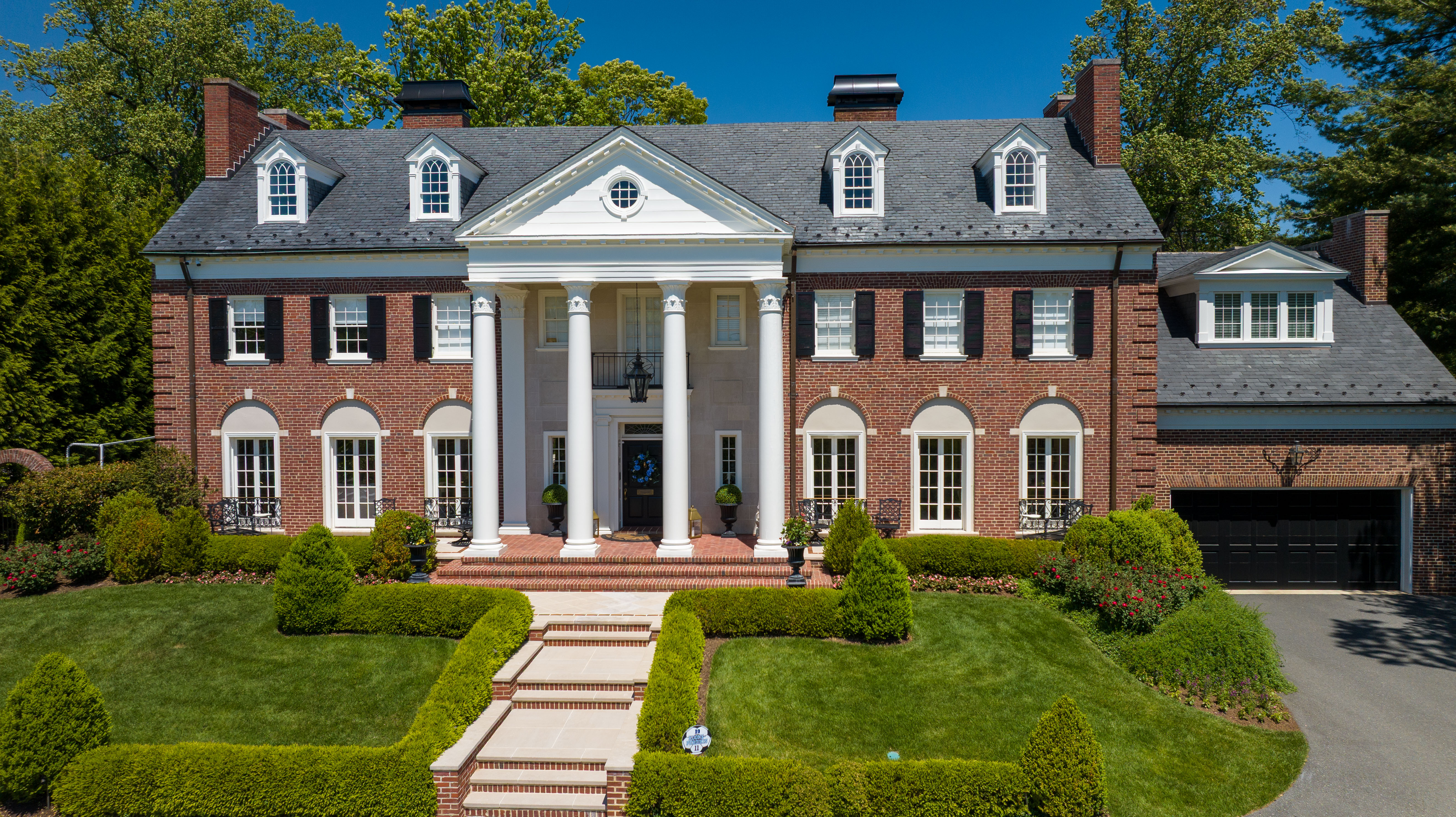 Aerial view of colonial mansion with columns and landscaping